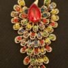 LARGE PEACOCK BROOCH 2'' WIDE X 4'' LONG GOLD-TONE WITH A LARGE RUBY COLORED CENTER STONE AND FULLY DECORATED WITHBRILLANT MULTI COLORED RHINESTONES